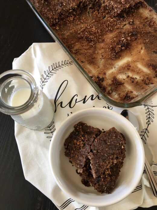 Double Chocolate Baked Oatmeal in a bowl with a pan of baked oatmeal in the background