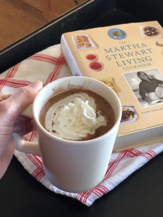 Martha Stewart's Hot Chocolate Recipe in mug with whipping cream and cookbook