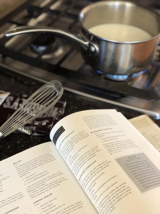 Cooking Martha Stewart's Hot Chocolate in a pan with Cookbook on counter