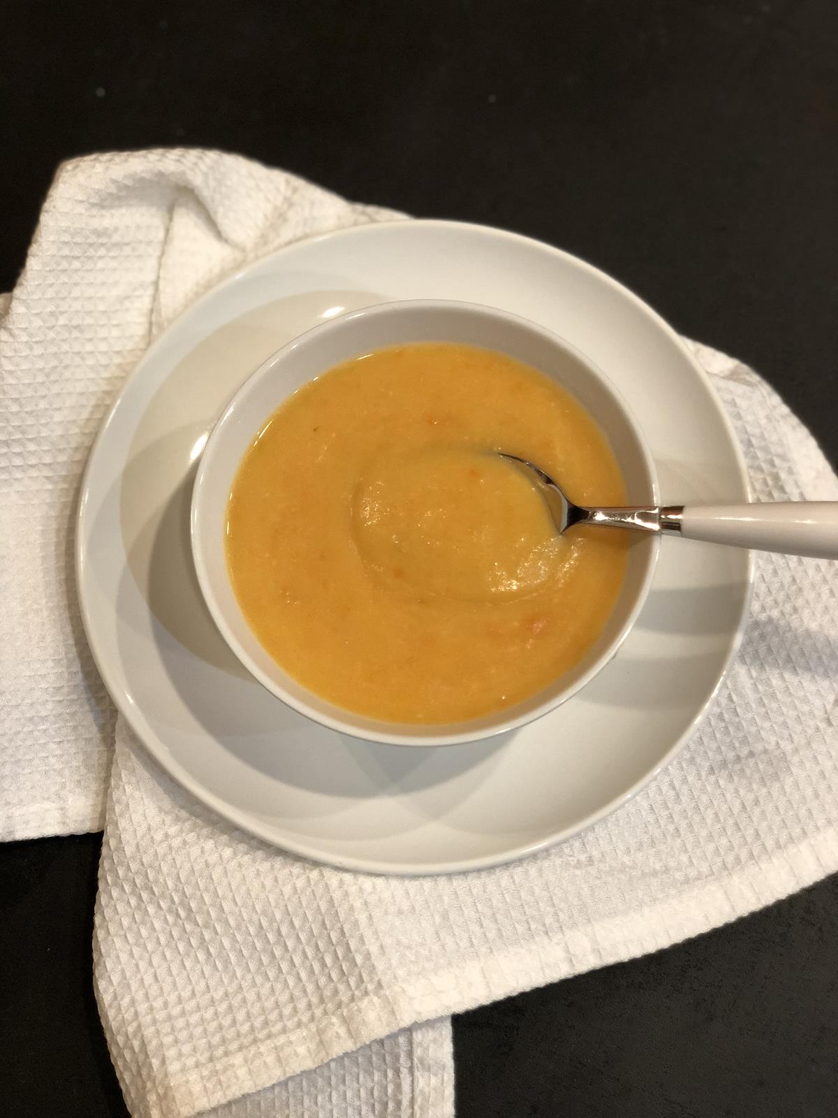 carrot soup in a white bowl with a spoon