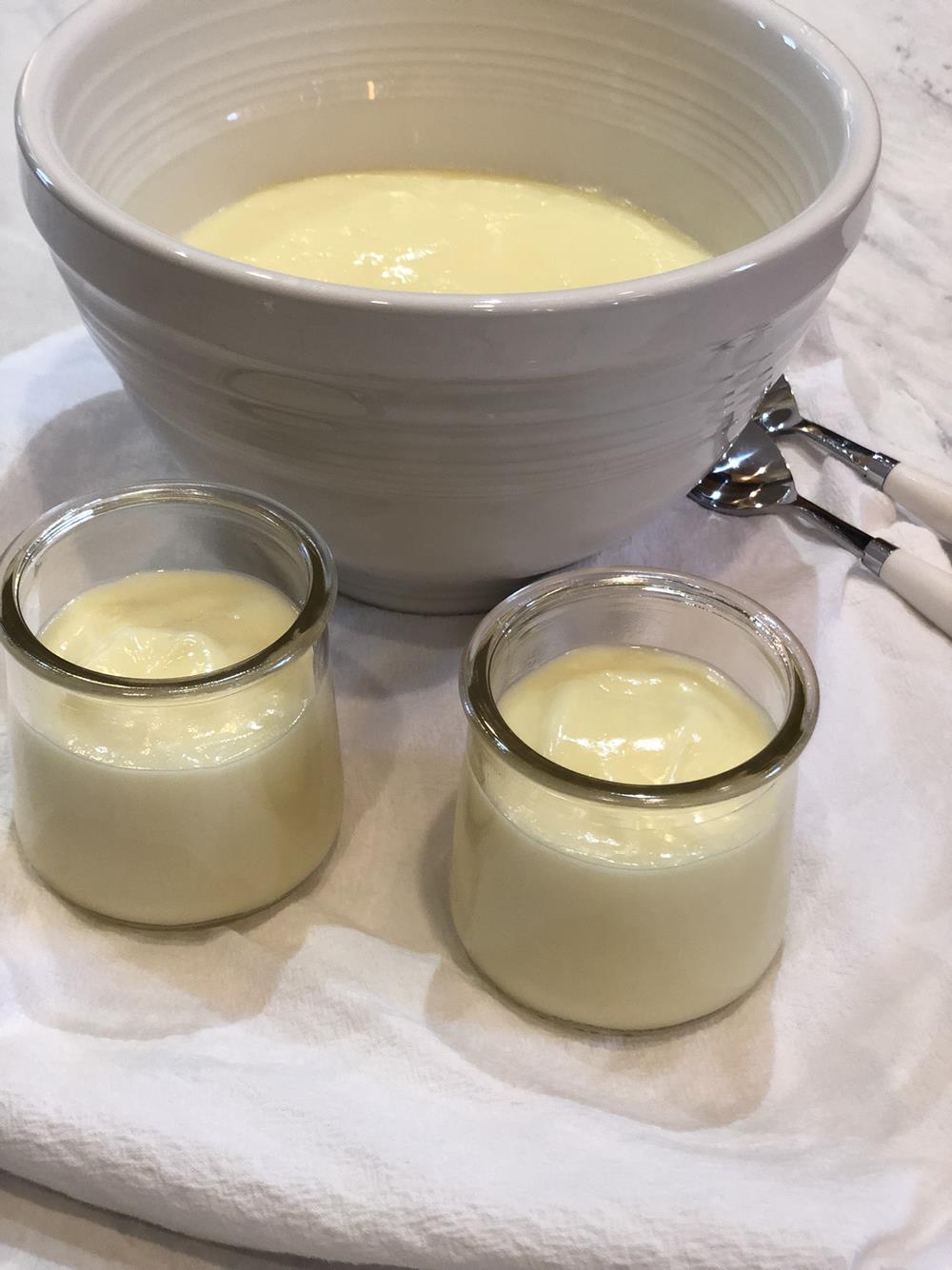 lemon pudding in white bowl with cups and spoons