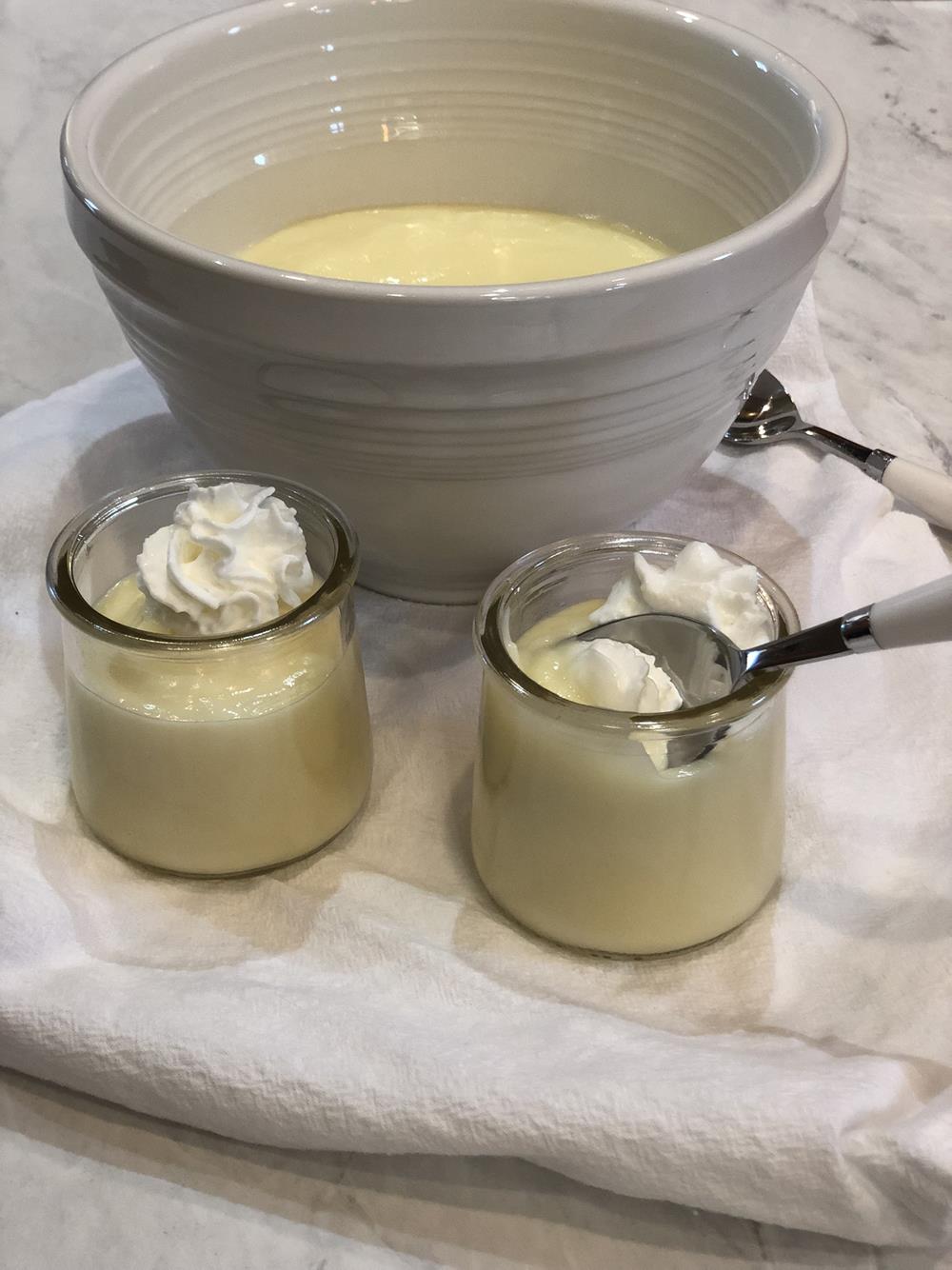 lemon pudding in white bowl with glass bowls and spoon