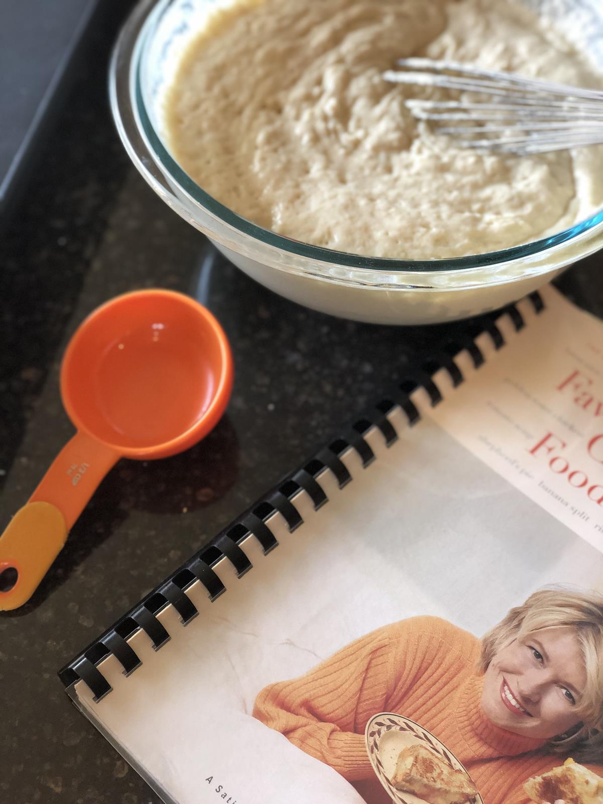 cookbook, measuring cup, and pancake batter