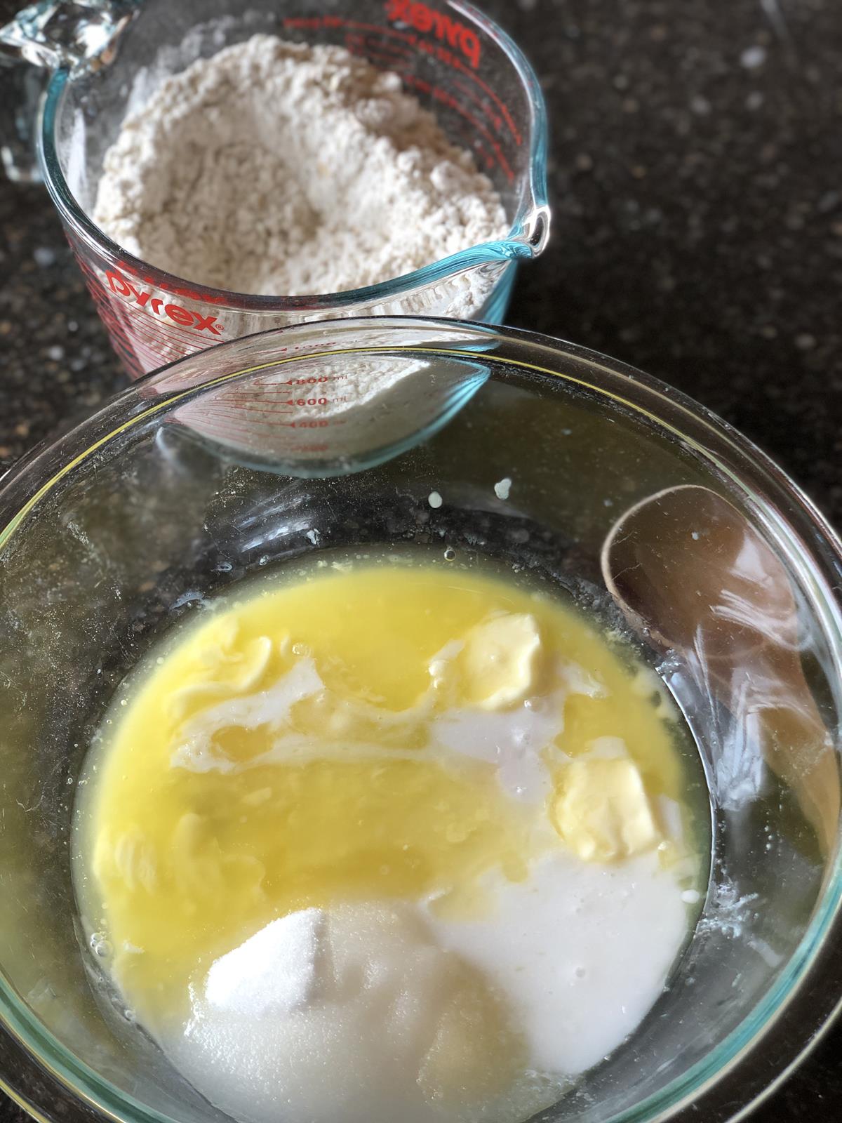 muffin batter in glass bowl with measuring cup in background