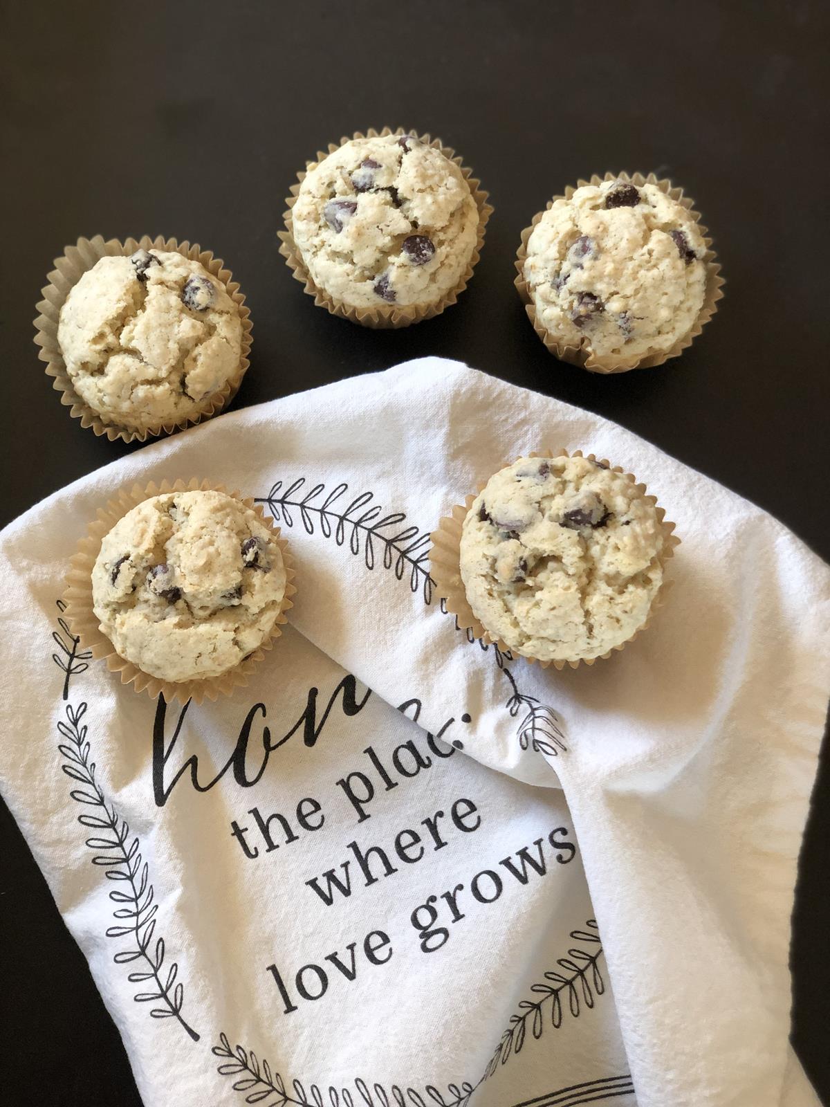 oatmeal chocolate chip muffins on a white kitchen towel on black counter