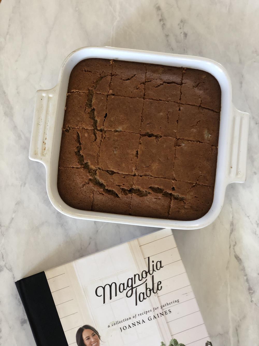 Banana bread in white pan with cookbook