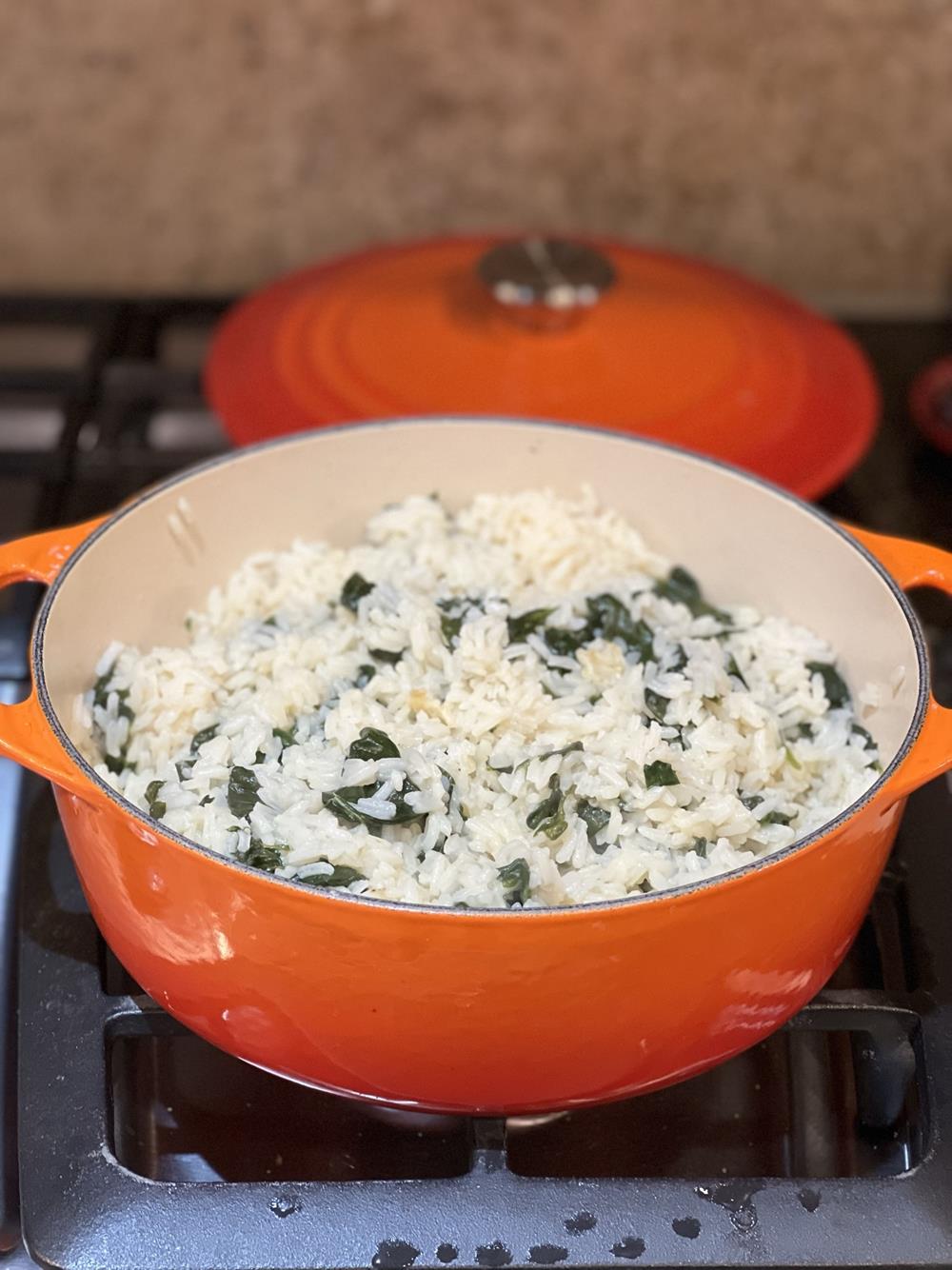 orange pot with rice and spinach on stove