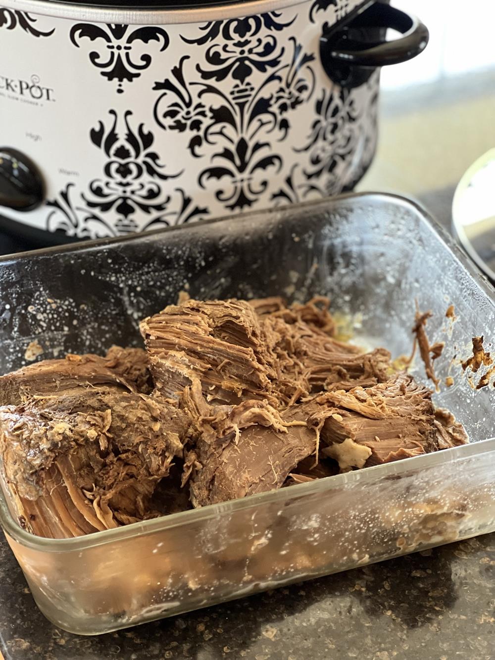 BBQ beef in glass dish with crockpot in background