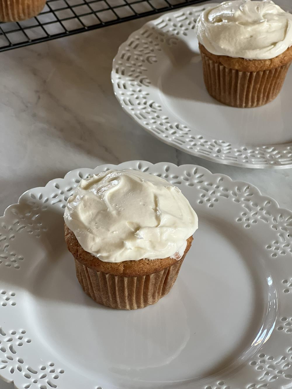banana cupcake with white frosting on white plate