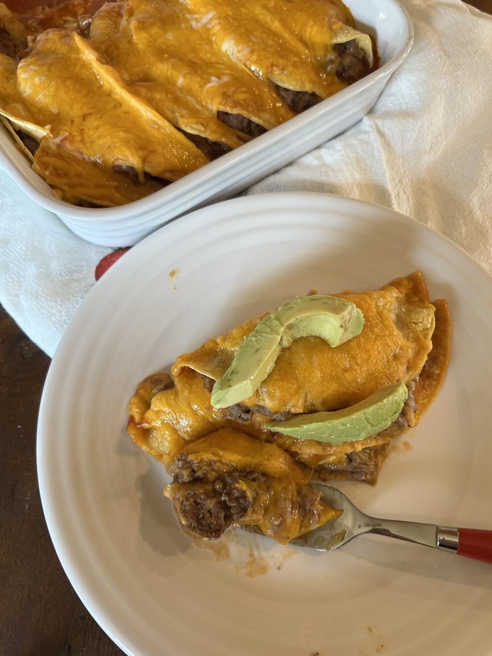 enchiladas on white plate with fork with red handled