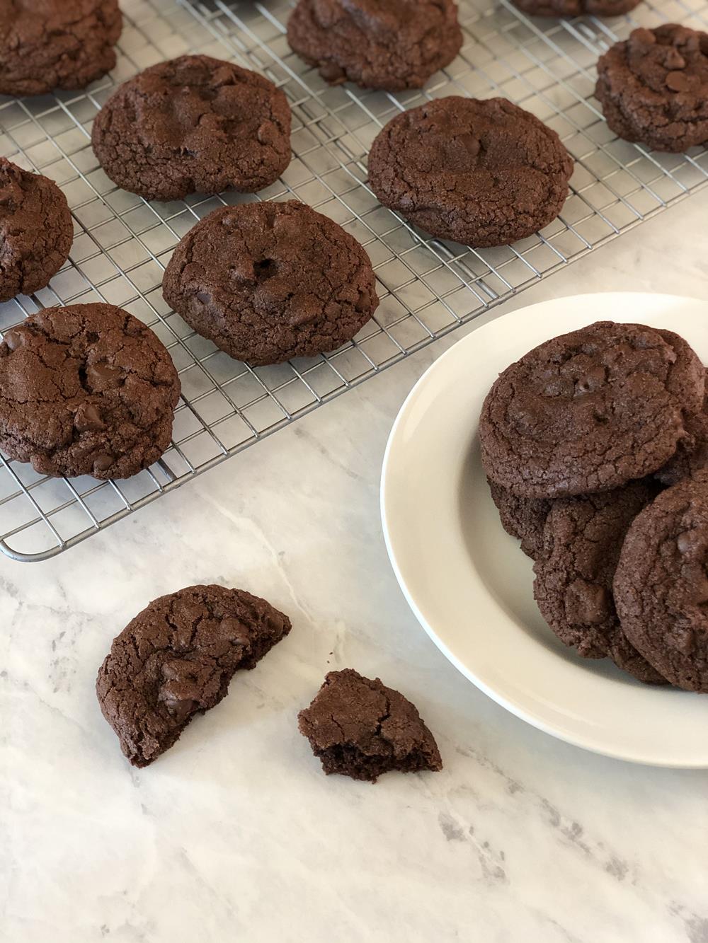 Gluten Free Chocolate cookies on white plate with cookie on marble counter