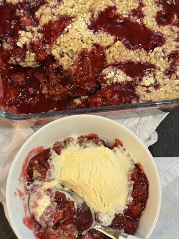 blackberry cobbler in white bowl with vanilla ice cream