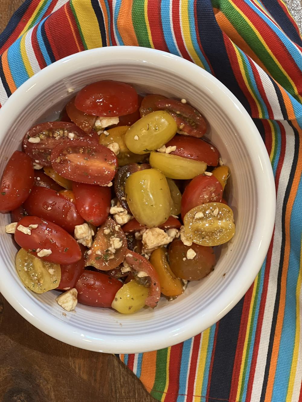 red and yellow tomatoes with feta cheese in a white bowl