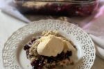 Blueberry Crisp on white plate with pan in background