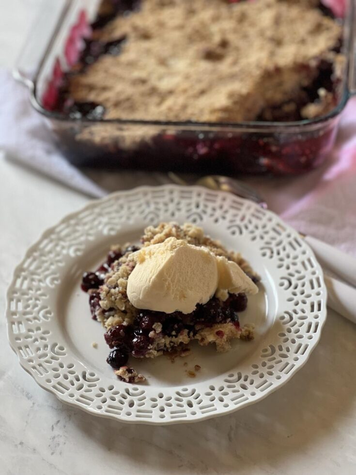 Blueberry Crisp on white plate with pan in background