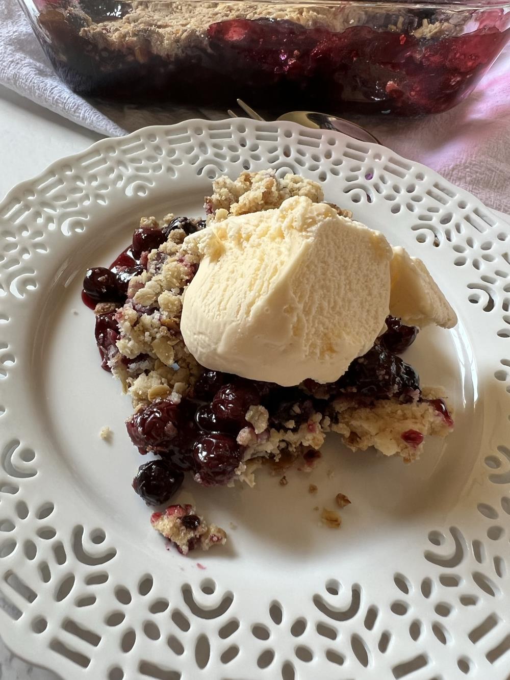 Blueberry Crisp on white plate with vanilla ice cream