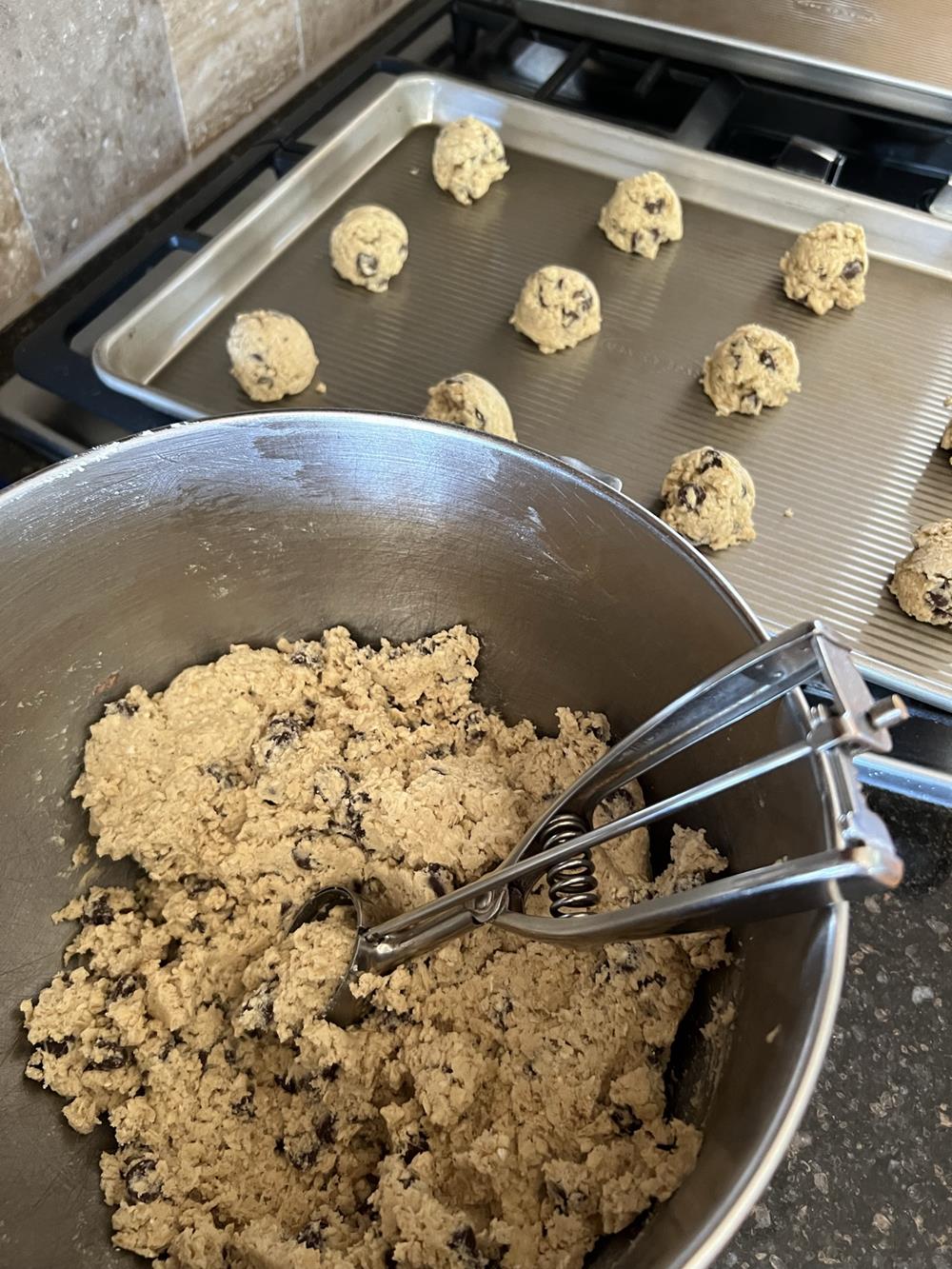 Chocolate Chip Oatmeal Cookie dough in bowl with cookie sheet in background