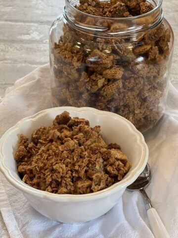 Peanut Butter Chex Granola in a white bowl with glass jar in background