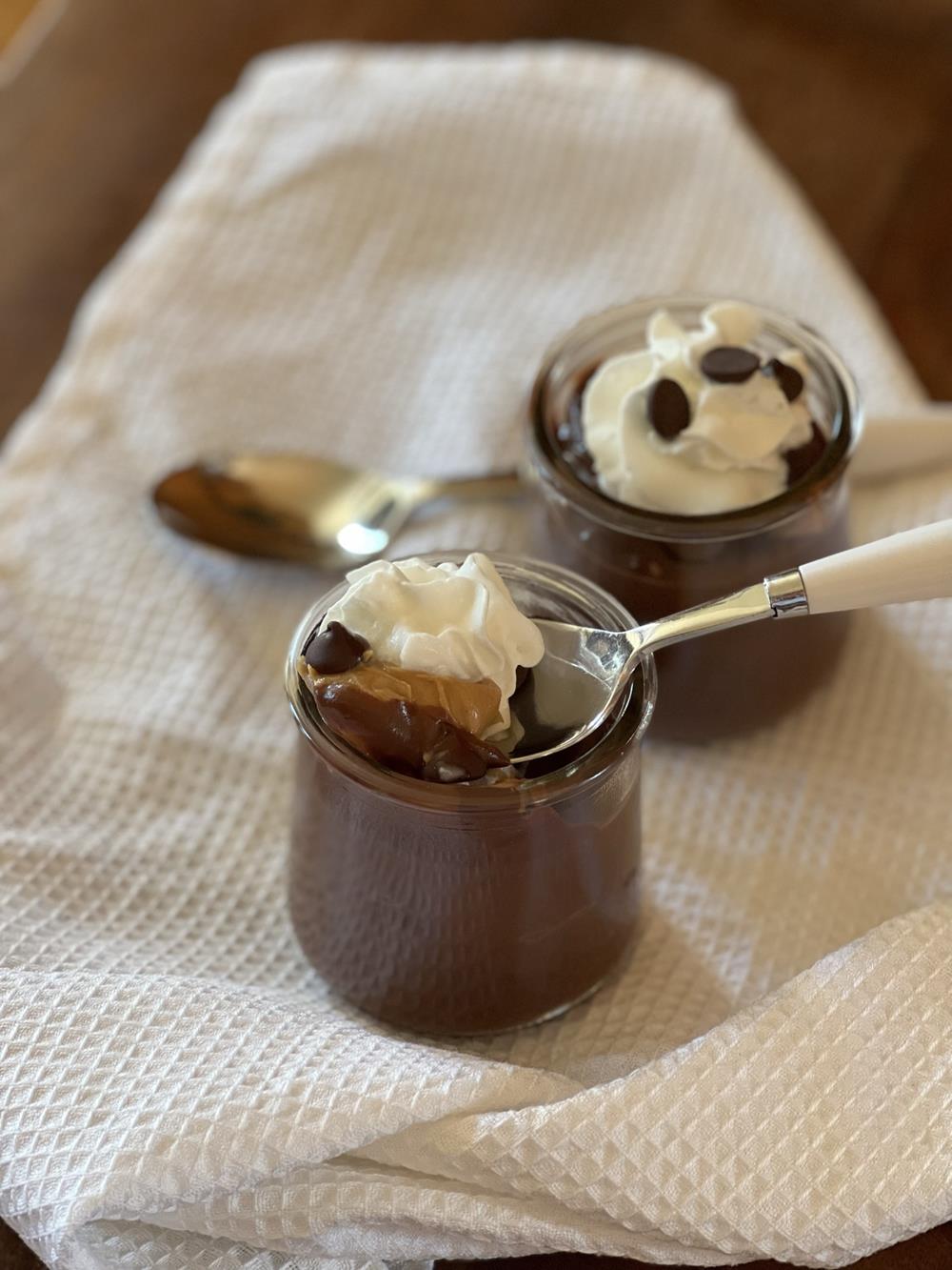 chocolate pudding with peanut butter in glass jar with spoon on white napkin