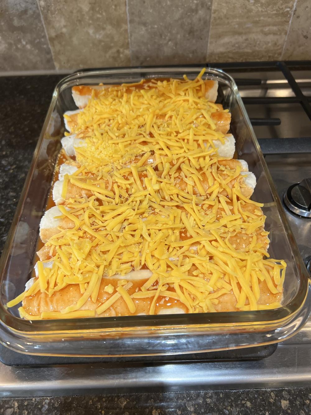 uncooked enchiladas in pan with cheese