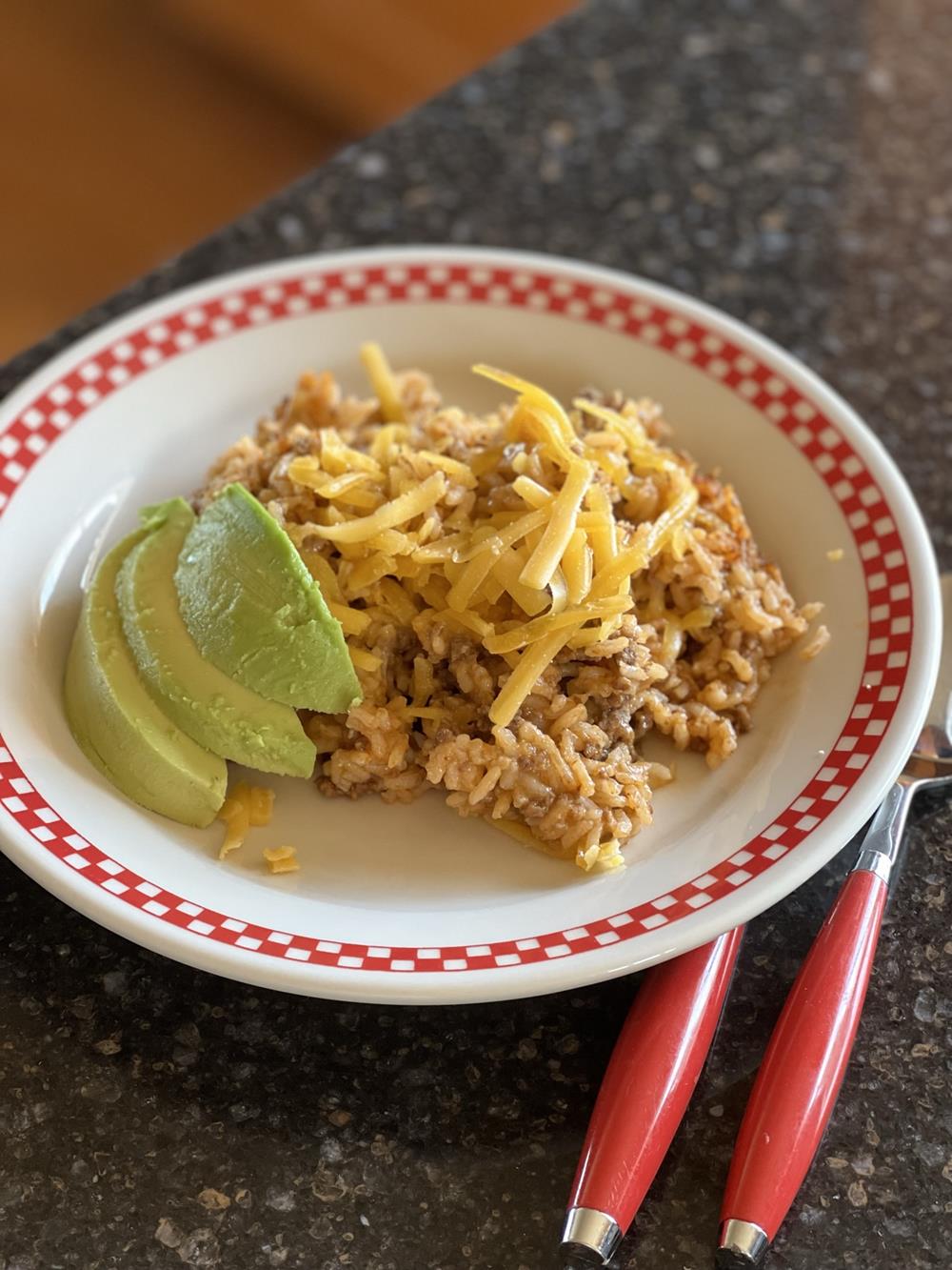 rice and ground beef with cheese and avocado on red and white plage