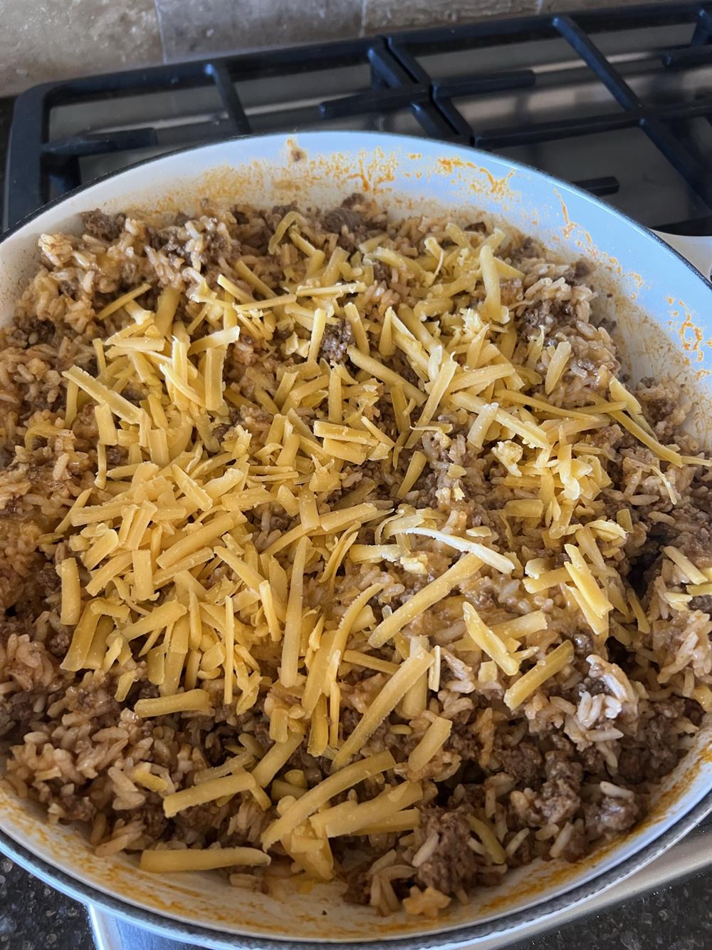 Mexican Rice with Ground Beef and Cheese in white pan on stove