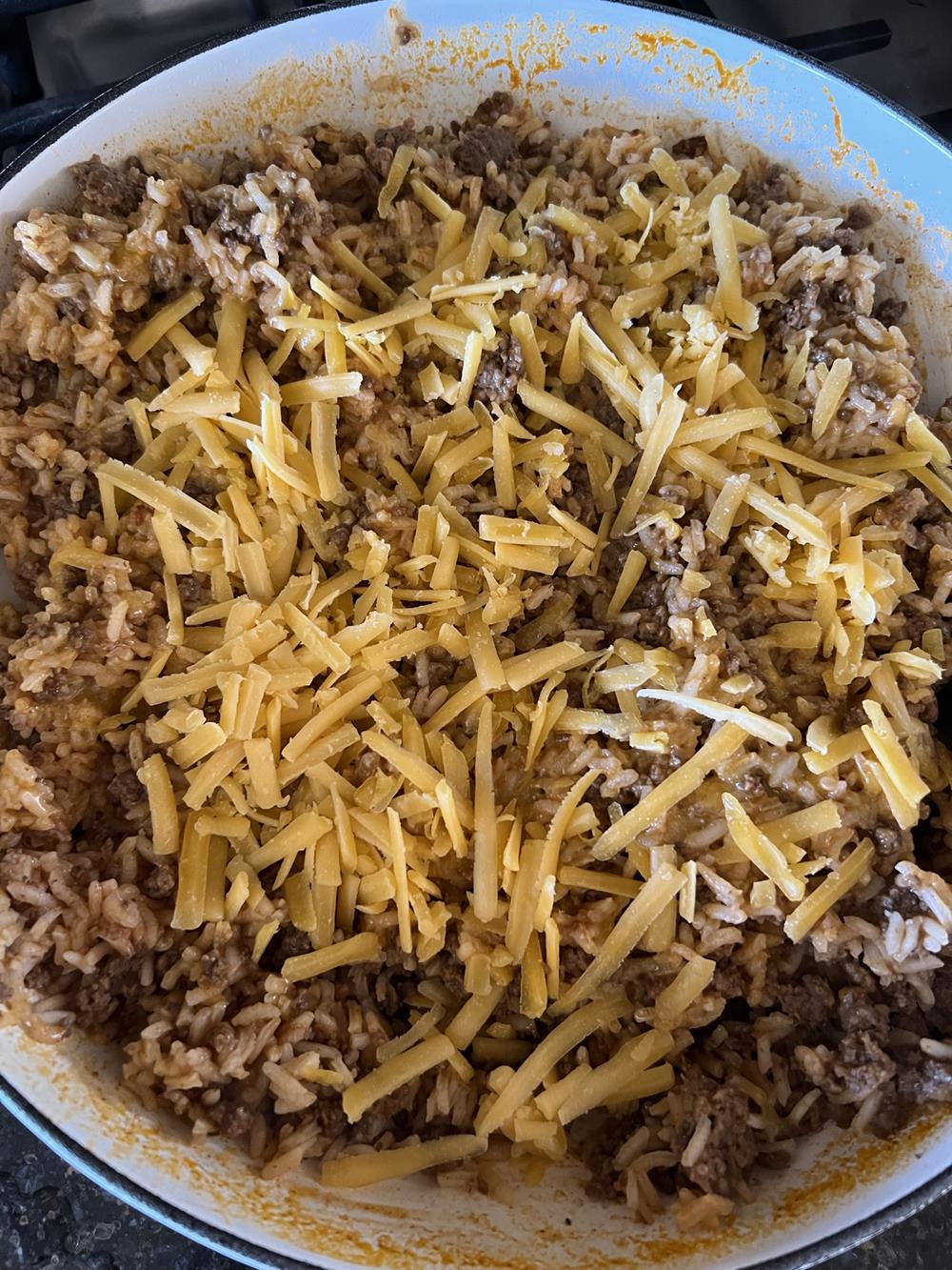 mexican rice with ground beef and cheese in white pot