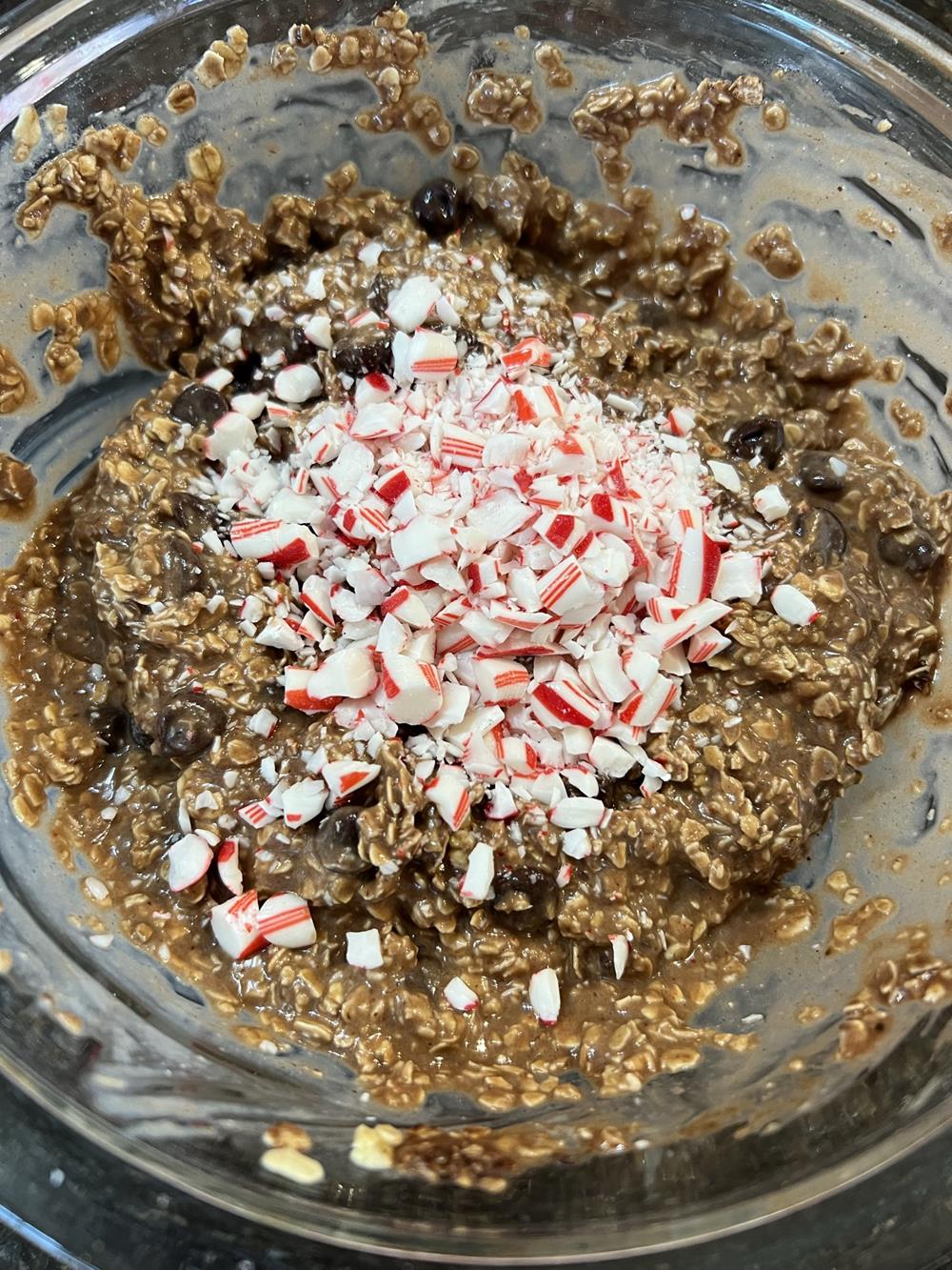 oatmeal, chocolate chips, eggs, candy canes and baked oatmeal ingredients in glass bowl