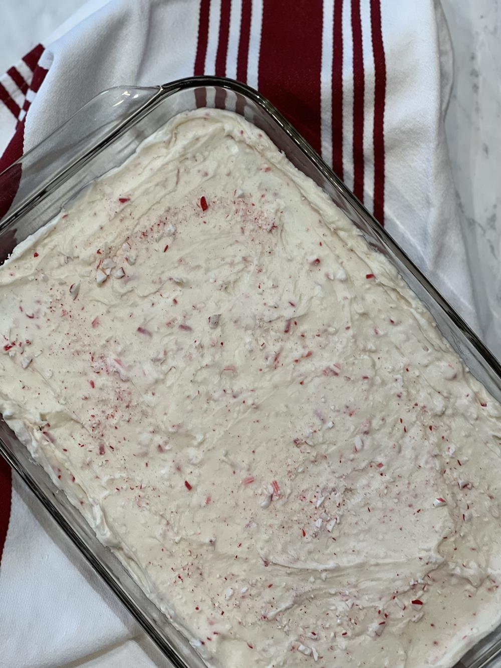 brownies with frosting in a glass pan with striped towel in background