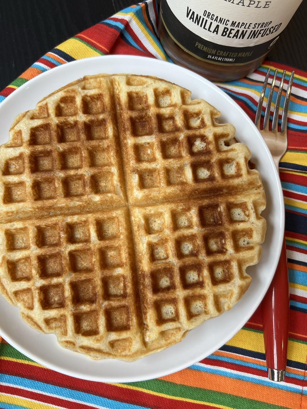 waffles on white plate with bottle of syrup in background