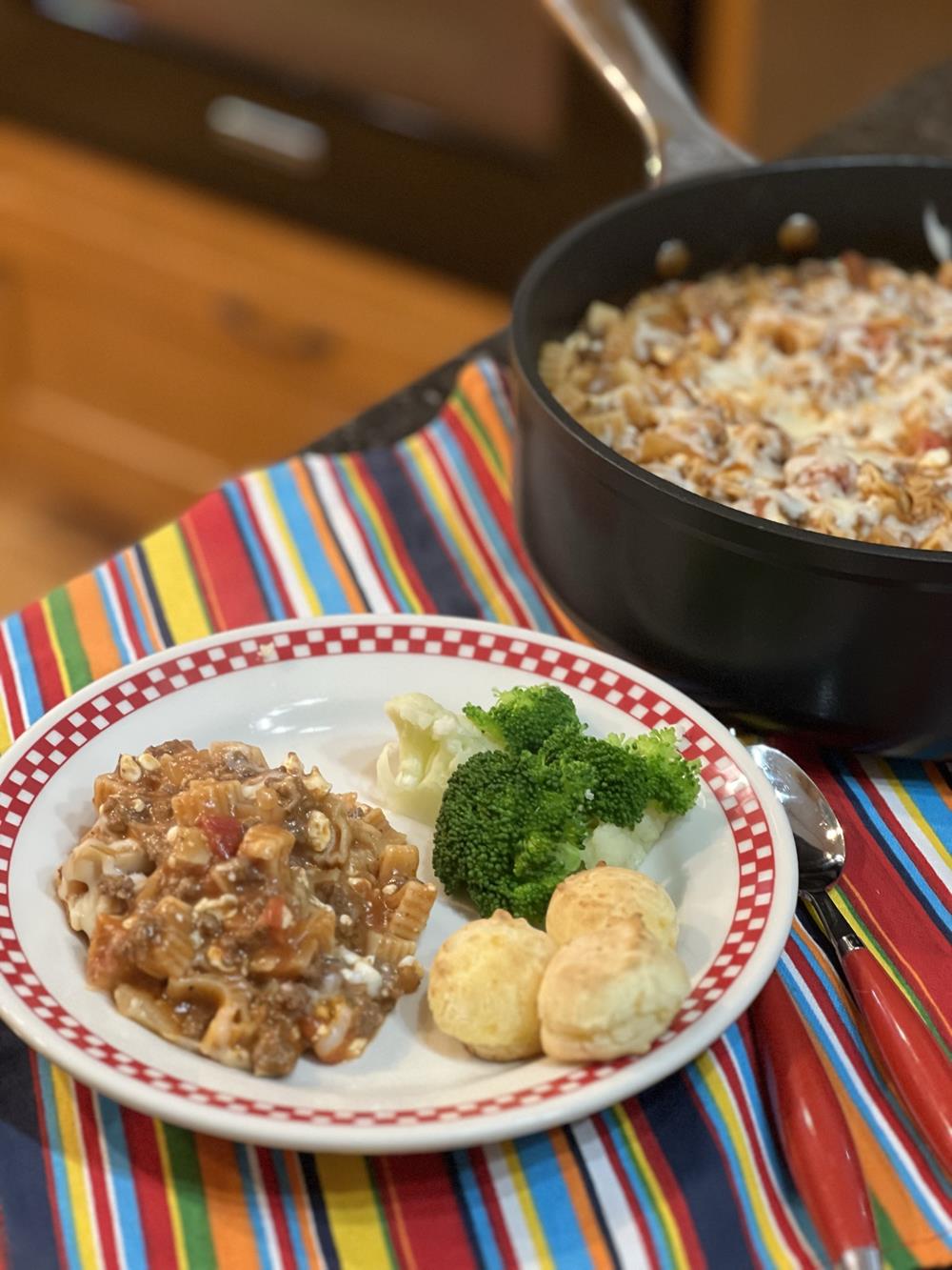 skillet lasagna on a plate with rolls and broccoli