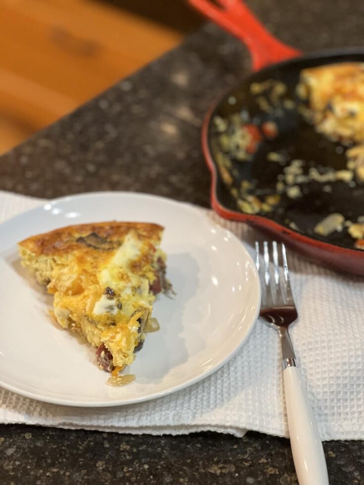 frittata on white plate with fork on white napkin