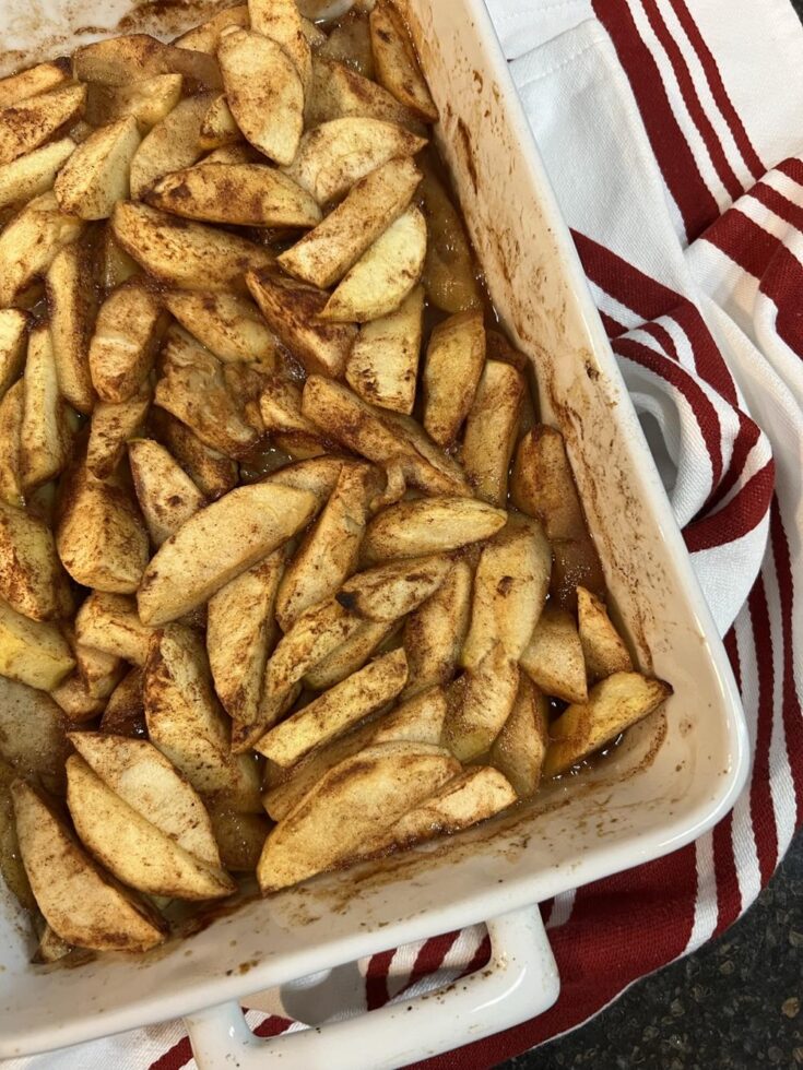 baked apples in a white dish on a red and white towel