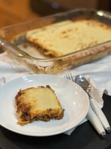 gluten free pizza casserole on a white plate with a pan of casserole in the background