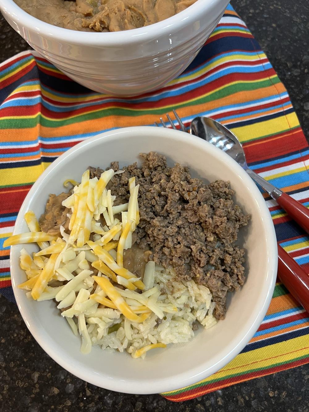 Cheesy Pinto Beans and rice in white bowl