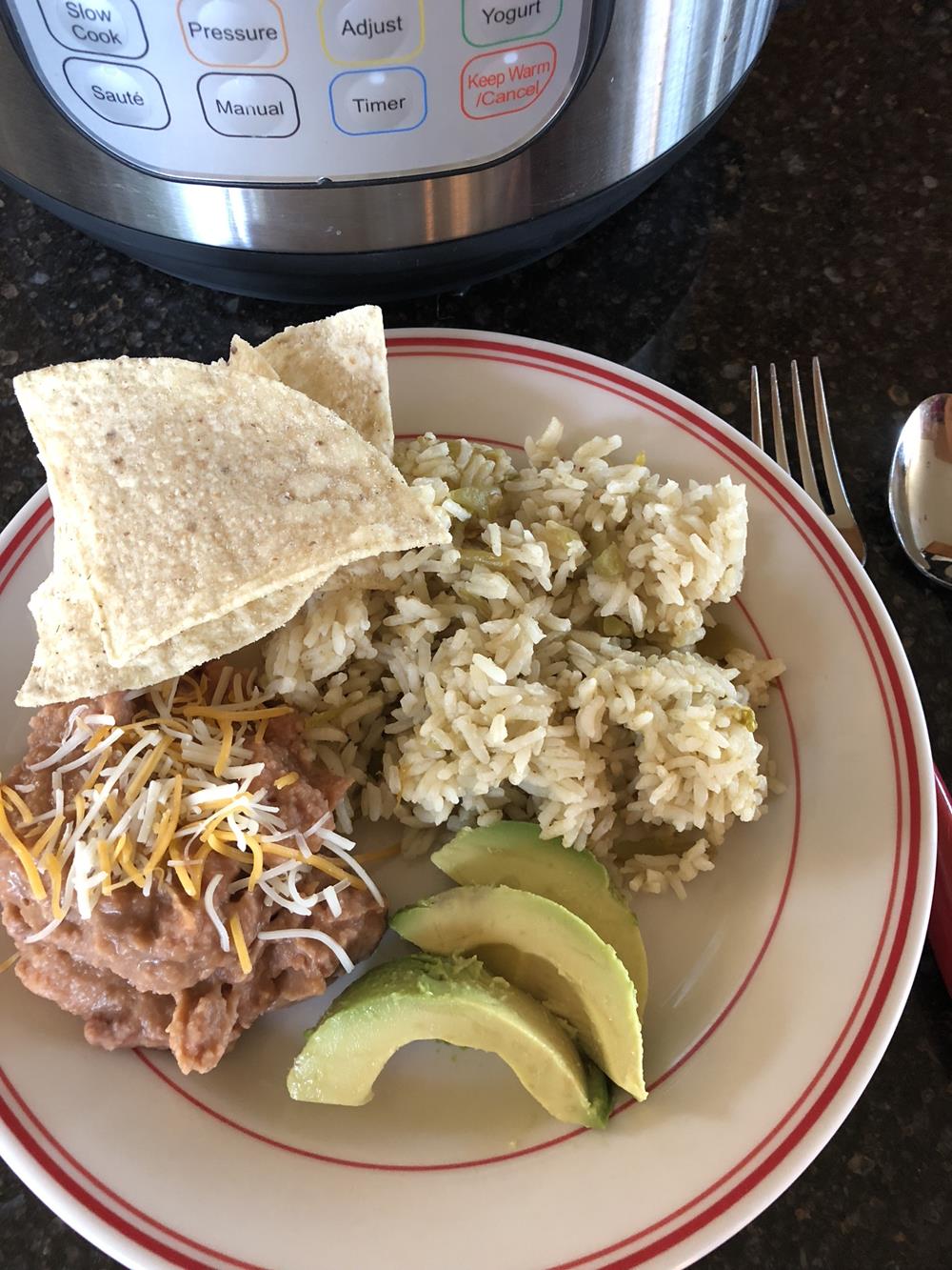 Instant Pot Green Chili Rice on a plate with beans, chips, and avocados