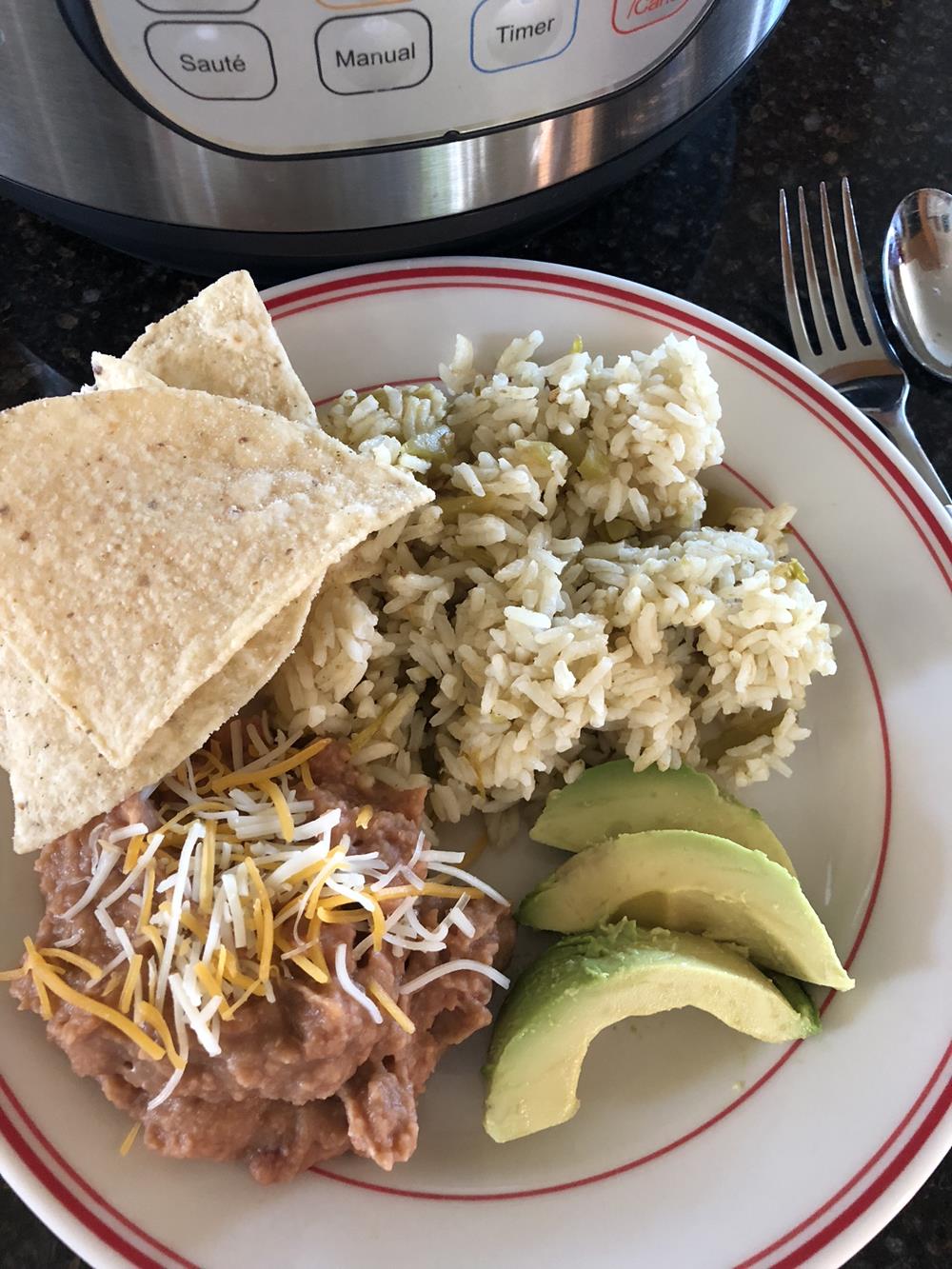 Green Chili Rice on a plate with beans, chips, and cheese