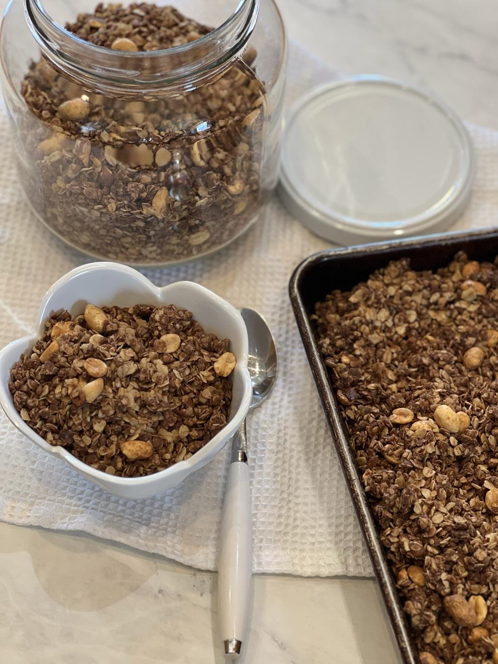 chocolate peanut butter granola on a cookie sheet with granola also in a bowl 