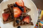 gluten free chocolate waffles with berries on white plate