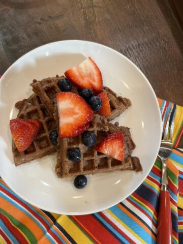gluten free chocolate waffles with berries on white plate