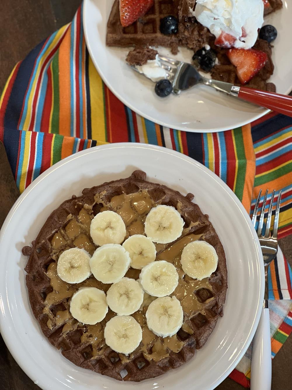 chocolate waffles with peanut butter and bananas on white plate