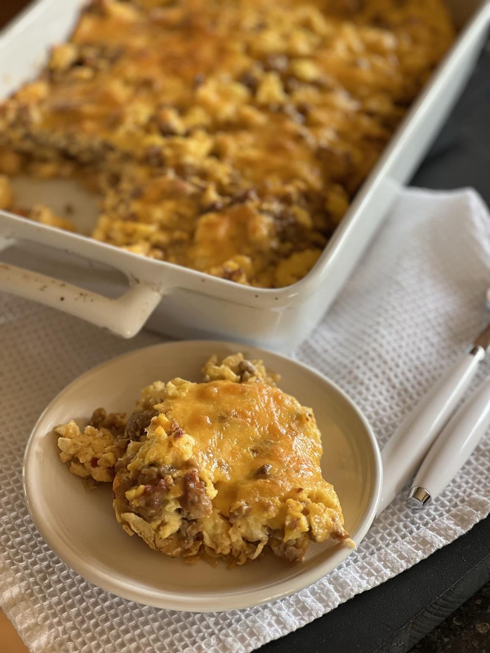 Breakfast casserole on white plate with white napkin in background