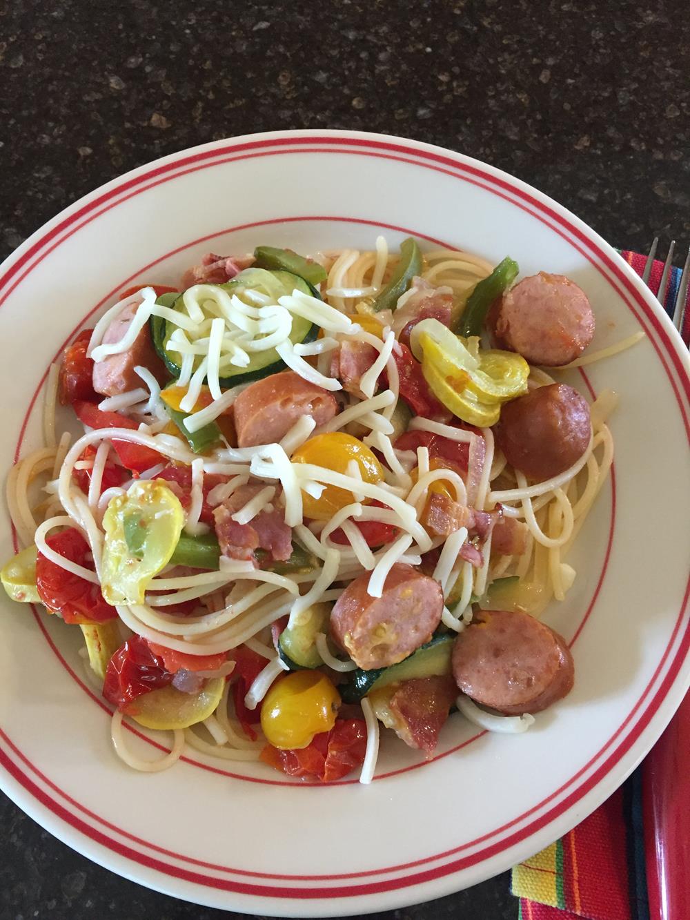 Pasta with Roasted Vegetables and Sausage on white plate with striped napkin in the background