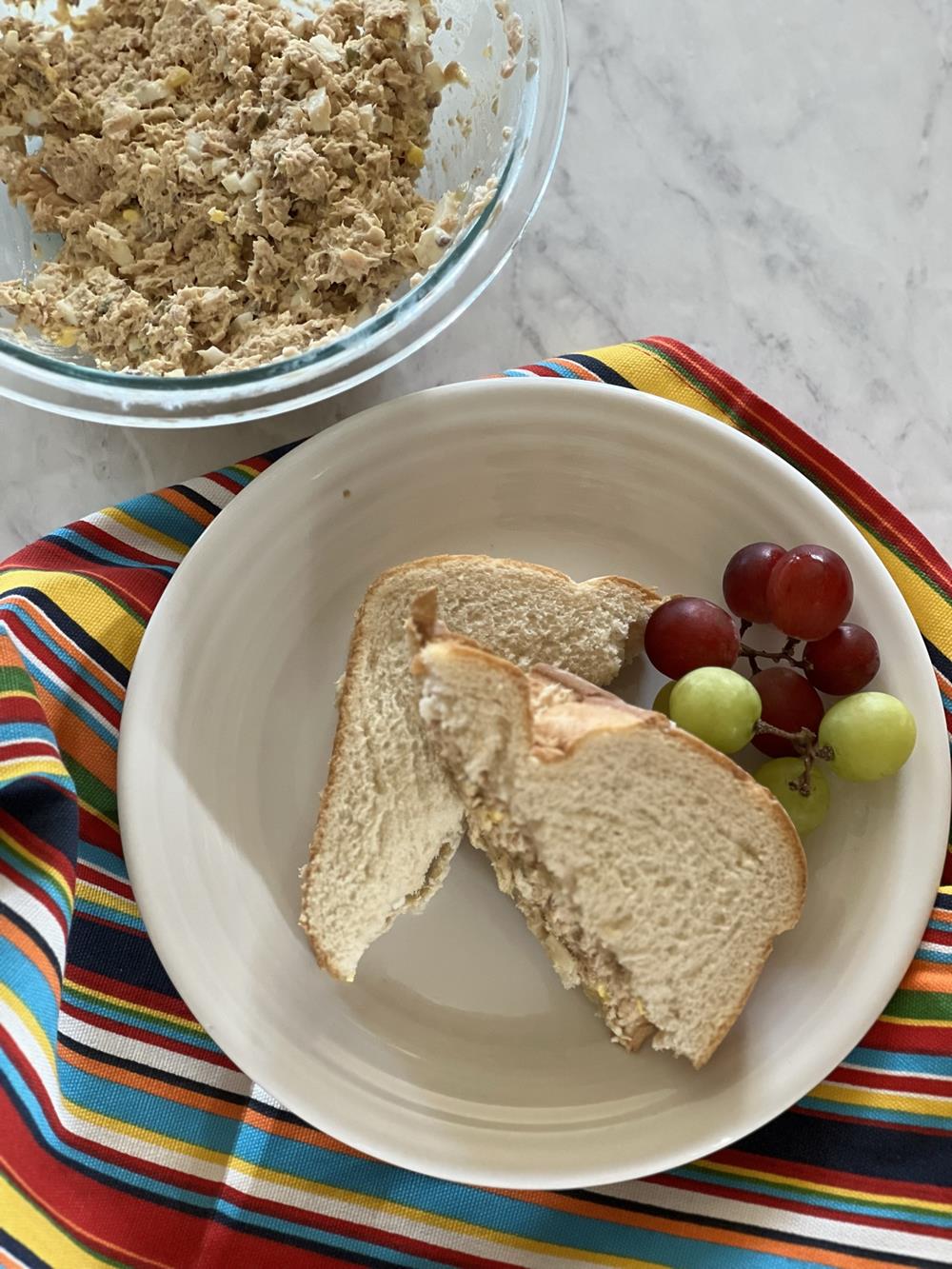 salmon salad sandwich and grapes on a plate