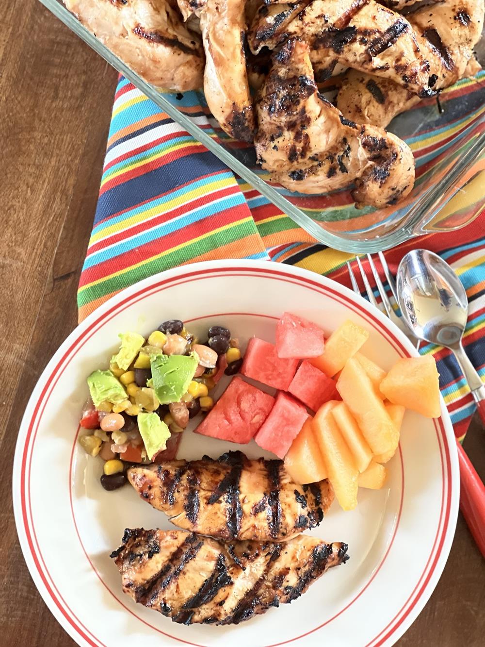 BBQ ranch chicken on red and white plate with dish of chicken in background