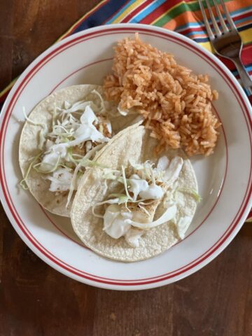 fish tacos on a plate with mexican rice