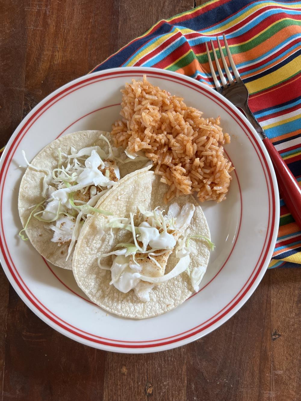 fish tacos on white and red plate with mexican rice