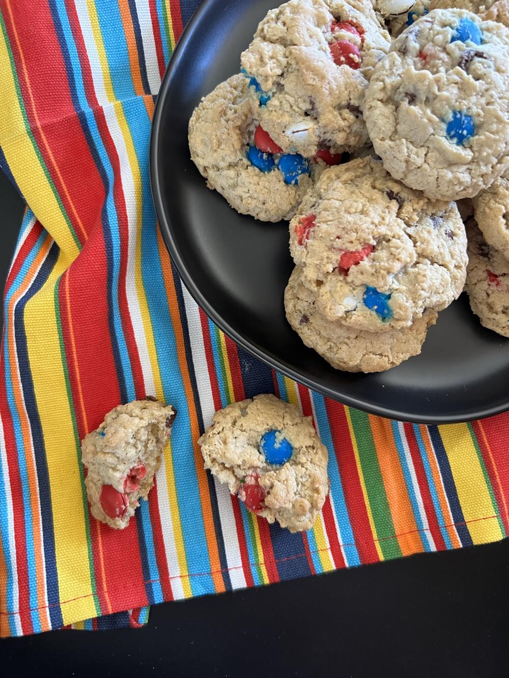 Oatmeal cookies one a black plate set on a striped napkin