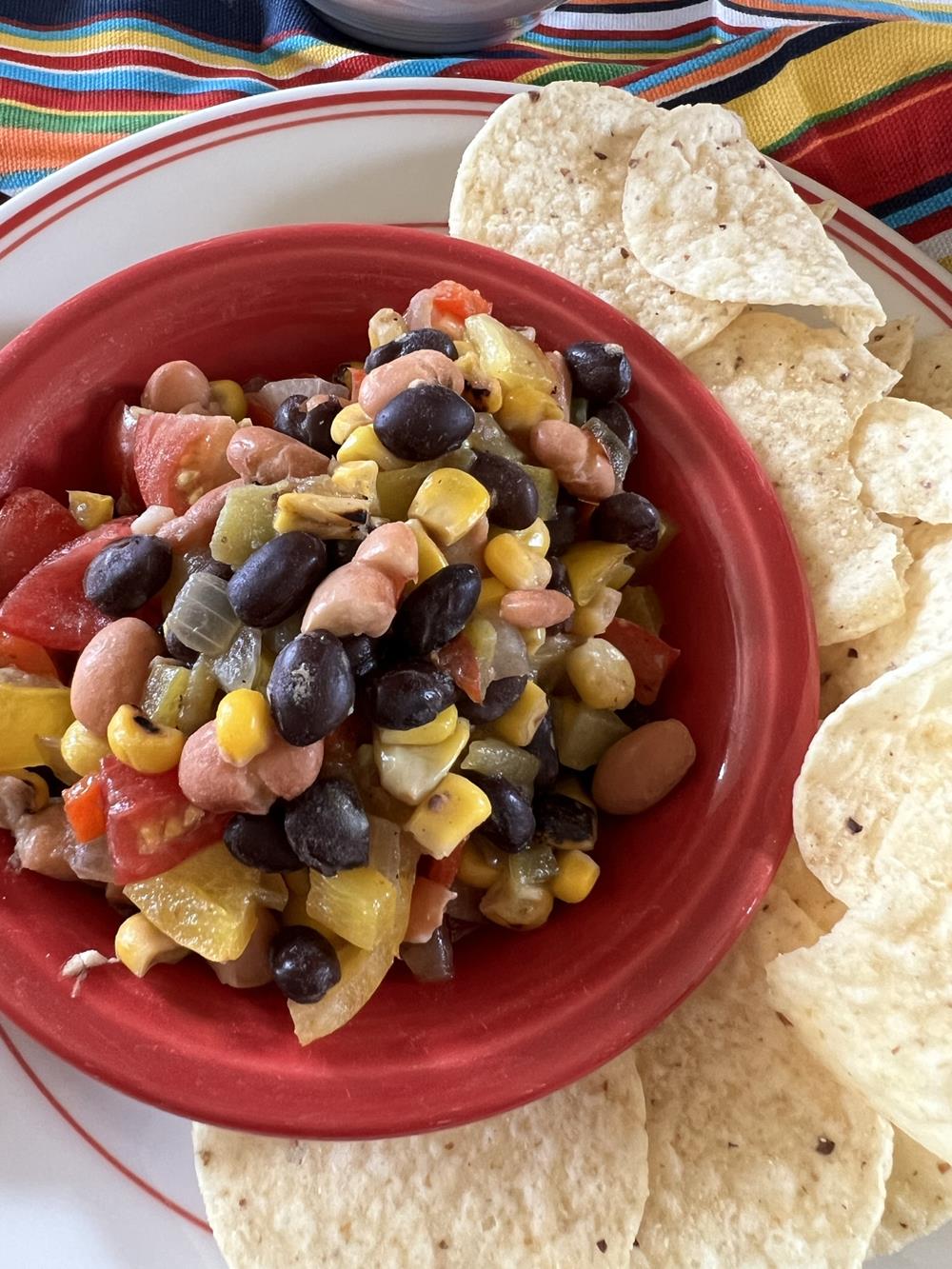 cowboy caviar in red bowl on white plate with chips