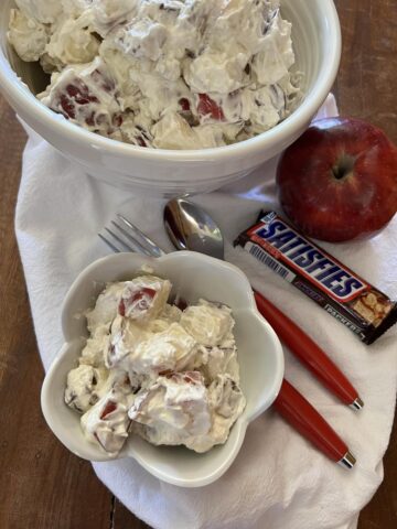 Snickers Bar Apple Salad in white bowl on white napkin